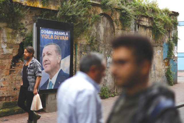  PEOPLE WALK past a sign in Istanbul on May 29 featuring Turkish President Recep Tayyip Erdogan, after he was declared the winner in the second round of the presidential election (credit: Hannah McKay/Reuters)