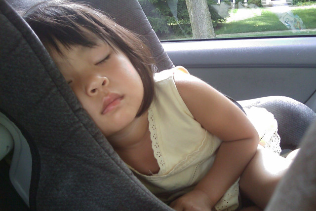  A young child is seen sleeping in a car (Illustrative). (credit: PXHERE)