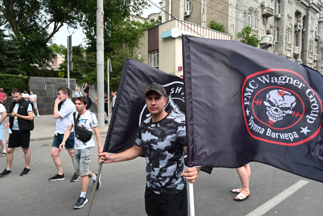 A supporter of Wagner private mercenary group holds flags near the headquarters of the Southern Military District controlled by Wagner fighters in the city of Rostov-on-Don, Russia, June 24, 2023. (credit: STRINGER/ REUTERS)