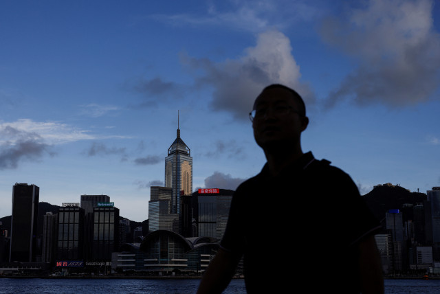  A man walks along the waterfront in front of Victoria Harbour, with the iconic skyline buildings as a backdrop, in Hong Kong, China June 28, 2023 (credit: REUTERS/TYRONE SIU)