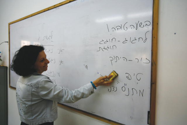  An ulpan teacher writes on a whiteboard in Hebrew. (credit: FLASH90)