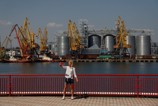  A woman takes a selfie with a grain terminal in a background in the sea port in Odesa after restarting grain export, as Russia's attack on Ukraine continues, Ukraine August 19, 2022. (credit: VALENTYN OGIRENKO/REUTERS)