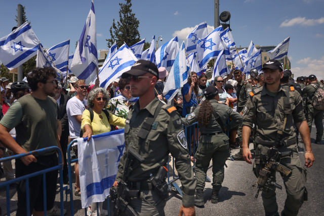  Israeli security forces stand guard in front of protesters waving national flags near the Parliament in Jerusalem, on July 11, 2023. (credit: Menahem Kahana/AFP via Getty Images)