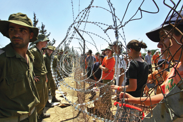  OPPONENTS OF Prime Minister Ariel Sharon’s disengagement plan face IDF troops as they secure the fence of Kfar Maimon in July 2005 after police blocked them from marching to the Gush Katif communities to protest against their demolition.  (credit: GIL COHEN MAGEN/REUTERS)