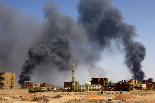  A man walks while smoke rises above buildings after aerial bombardments during clashes between the paramilitary Rapid Support Forces and the army in Khartoum North, Sudan, May 1, 2023.  (credit: REUTERS/Mohamed Nureldin Abdallah/File Photo)