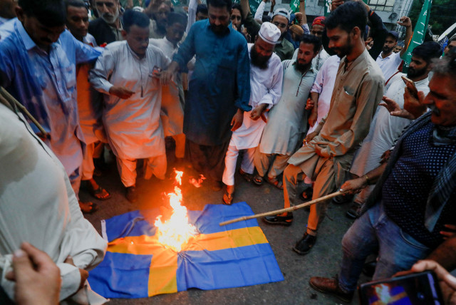  Supporters of the Tehreek-e-Labbaik Pakistan (TLP), a religious and political party, burn a Swedish flag during a protest to denounce the desecration of Koran outside a mosque in the Swedish capital Stockholm, in Karachi, Pakistan July 7, 2023.  (credit: REUTERS/AKHTAR SOOMRO)