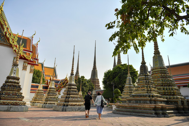 A couple walks at an empty Wat Po temple in Bangkok, Thailand, March 3, 2020.  (credit: REUTERS/Chalinee Thirasupa)