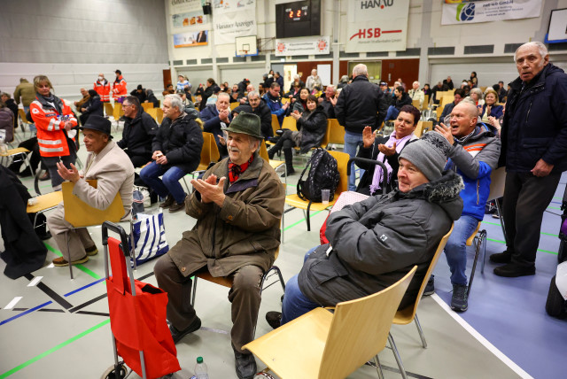 People in a shelter applaud after the announcement of controlled detonation of a World War II bomb that was found on the factory site of German industrial giant Heraeus in Hanau, Germany, March 1, 2023. (credit: REUTERS/KAI PFAFFENBACH)