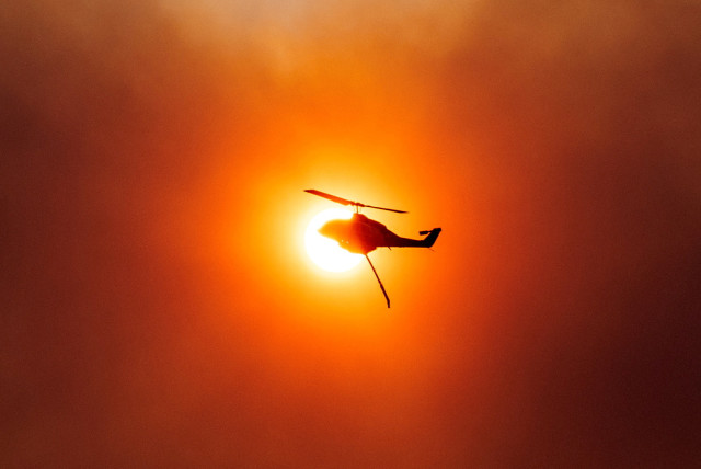  A firefighting helicopter is silhouetted in front of the sun, as a wildfire burns in Mandra, Greece, July 18, 2023. (credit: ALKIS KONSTANTINIDIS / REUTERS)