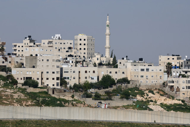  PALESTINIAN RESIDENTIAL buildings and a mosque are seen beyond Israel’s separation wall surrounding the Shuafat refugee camp in east Jerusalem. (photo credit: GILI YAARI/FLASH90)