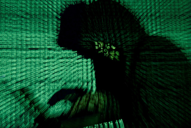 A man holds a laptop computer as cyber code is projected on him in this illustration picture taken on May 13, 2017. (credit: KACPER PEMPEL/ILLUSTRATION PHOTO/REUTERS)