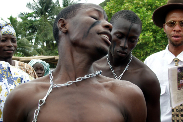 Nigerian Kehinde Avose wears chains on his neck while re-enacting the days of slavery for American visitors in the former slave port of Badagry town south-west Nigeria August 25, 2002. More than fifty black Americans, including seven mayors, are in Lagos for the Second Black Heritage Festival. (credit: REUTERS/George Esiri GE/CLH/)