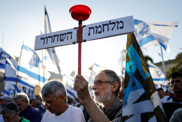  Israelis take part in a protest where military reservists sign pledge to suspend voluntary military service if the government passes judicial overhaul legislation near the defence ministry in Tel Aviv, Israel July 19, 2023. The placard in Hebrew reads ''The War of liberation''. (credit: REUTERS/AMIR COHEN)