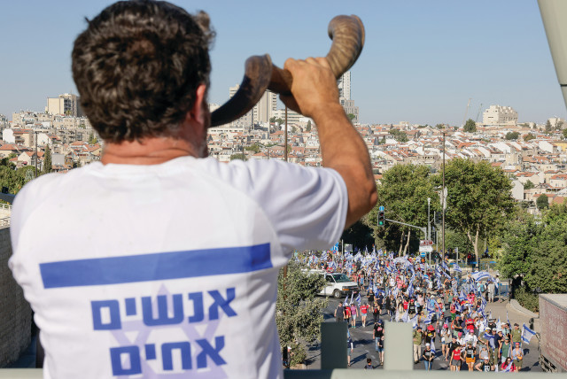  A MAN wearing a T-shirt with the slogan ‘We are all brothers’ blows a shofar near the Supreme Court in Jerusalem, calling for unity with the anti-reform demonstrators. (photo credit: MARC ISRAEL SELLEM/THE JERUSALEM POST)