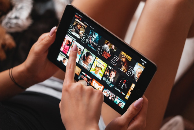  A woman scrolls through shows and movies on Netflix's mobile app. (credit: PIXABAY)