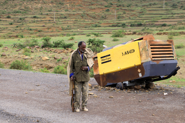  A Tigrayan Militia member stands next to construction machinery destroyed during the fighting between the Tigray People's Liberation Front (TPLF) and Ethiopian National Defence Force (ENDF) allied with Amhara Special Forces and Eritrean Defence Forces (EDF) on the outskirts of Samre, Ethiopia. (credit: Tiksa Negeri/Reuters)