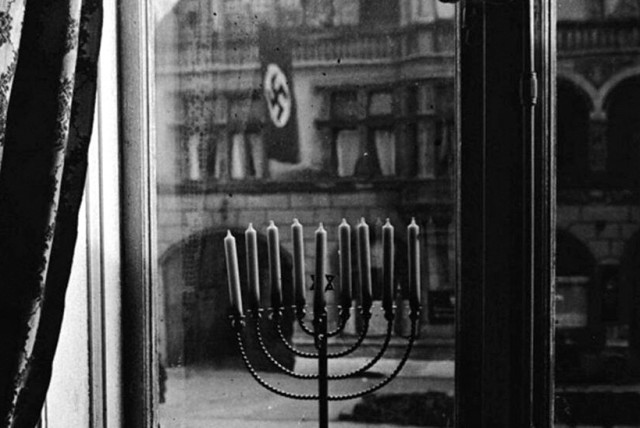  The iconic photo of a Hanukkah menorah with Nazi flags waving across the road, taken by Rachel Posner, wife of Rabbi Akiva Posner, in Kiel, Germany, 1931.  (credit: YAD VASHEM)