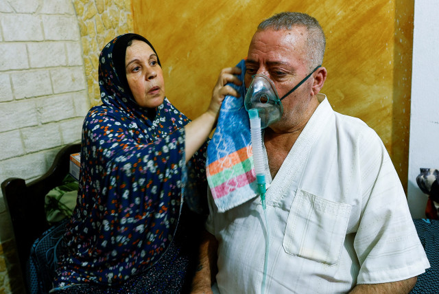  Aisha Nashwan helps her husband Ismail Nashwan at their house amid a heatwave in Al Burij refugee camp, central Gaza Strip, August 9, 2023. (credit: IBRAHEEM ABU MUSTAFA/REUTERS)