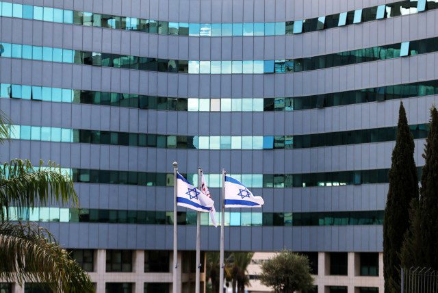  Israeli national flags flutter in front of an office tower at a business park also housing high tech companies, at Ofer Park in Petah Tikva, Israel August 27, 2020. (credit: REUTERS/Ronen Zvulun)