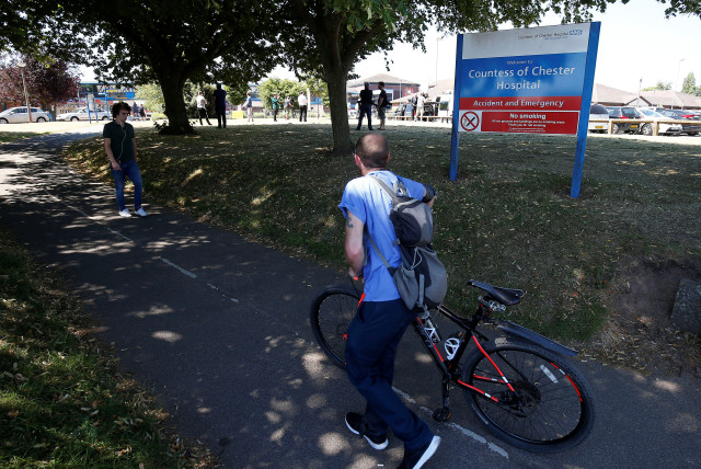 A man pushes his bike past the entrance to the Countess of Chester Hospital, Chester, Britain, July 3, 2018. (credit: ANDREW YATES/REUTERS)