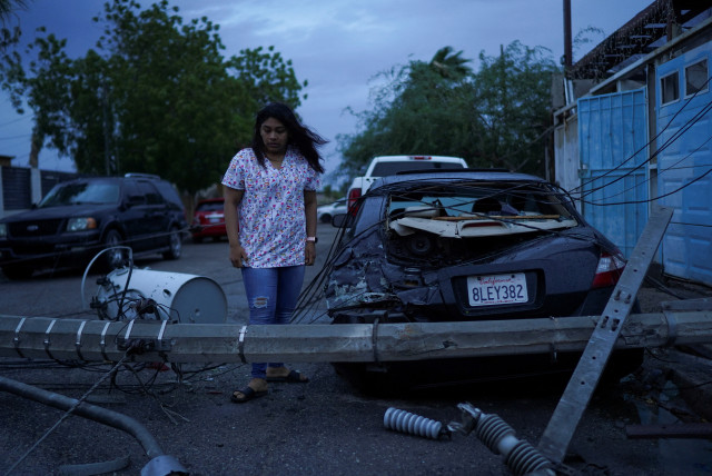  Laura Elizalde Reyes looks at a light pole that hit her car as Tropical Storm Hilary hits Baja California state, in Mexicali, Mexico, August 20, 2023. (credit: REUTERS/Victor Medina)