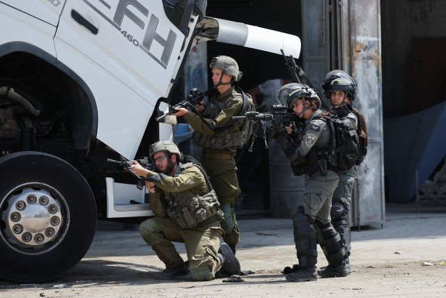 Israeli troops stand guard, near the scene of a shooting, near Hebron, in the West Bank August 21, 2023. (credit: MUSSA QAWASMA/REUTERS)