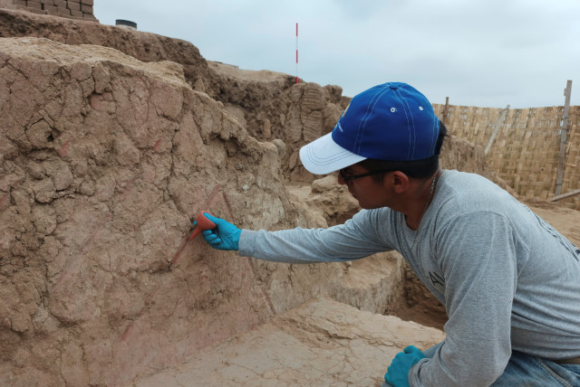 An archaeologist works on a 4,500-year-old polychrome wall, part of a temple belonging to the Late Preceramic period, in the Huaca Tomabal in the Valley of Viru, Peru August 24, 2023. (credit: Castillo/PAVI/Handout via REUTERS)