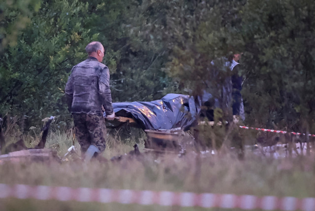 Emergency specialists carry a body bag near wreckages of the private jet linked to Wagner mercenary chief Yevgeny Prigozhin at the crash site in the Tver region, Russia, August 24, 2023. (credit: REUTERS/MARINA LYSTSEVA)