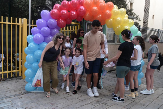  Children and their parents pass through a rainbow balloon arch on the first day of school in Israel on September 1, 2023. (credit: AVSHALOM SASSONI/MAARIV)
