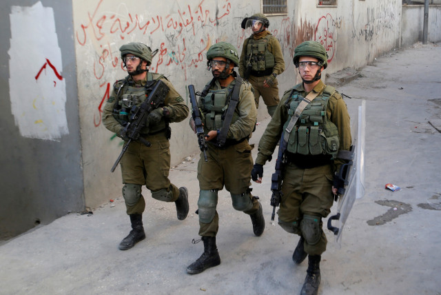 Israeli soldiers walk in the Palestinian al-Arroub refugee camp, in the West Bank November 12, 2019. (photo credit: MUSSA QAWASMA/REUTERS)