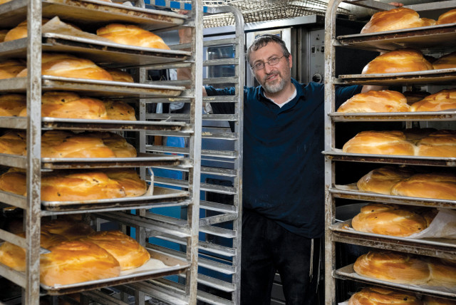  Israel Roling, the owner of Roling’s Bakery, stands between hundreds of loaves of ‘challah’ prepared for Rosh Hashanah in Elkins Park, Pennsylvania. (credit: RACHEL WISNIEWSKI/REUTERS)
