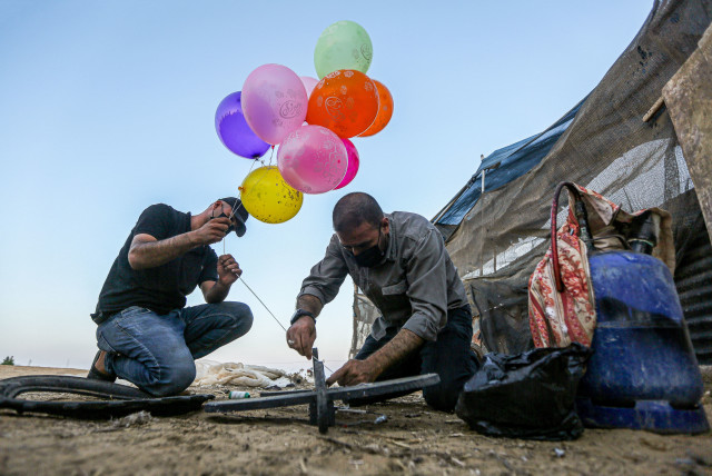  Masked Palestinians prepare a flammable object to be flown toward Israel, near the Israel-Gaza border, east of Khan Yunis in the southern Gaza Strip. September 19, 2023. (credit: Yousef Mohammed/Flash90)