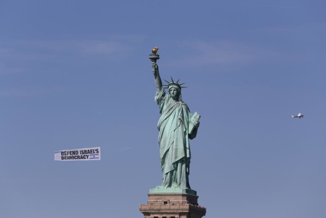  Banners flying against Israel's judicial reform fly past the Statue of Liberty. (credit: ROI BOSHI)