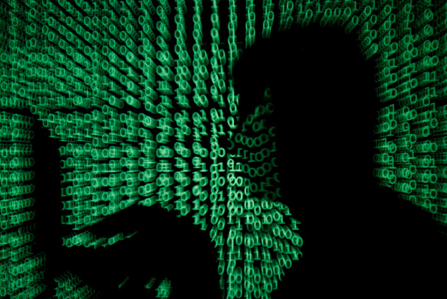  A man holds a laptop computer as cyber code is projected on him in this illustration picture taken on May 13, 2017. (credit: REUTERS/KACPER PEMPEL/ILLUSTRATION/FILE PHOTO)
