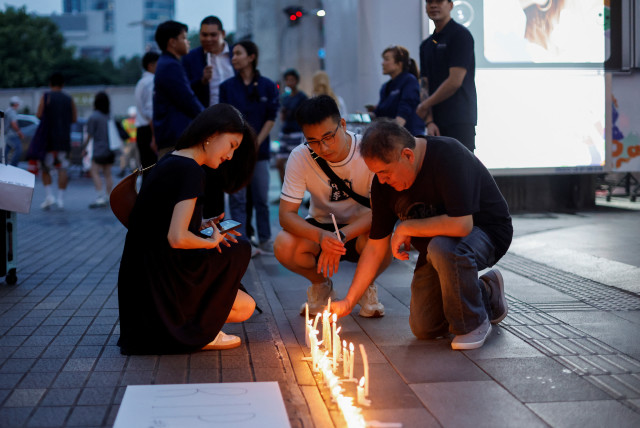  Helen Yi, a tourist from Taiwan, looks at candles placed outside the luxury Siam Paragon shopping mall where Thai police arrested a teenage gunman who is suspected of killing foreigners and wounding other people in a shooting, in Bangkok, Thailand, October 4, 2023. (credit: REUTERS/JORGE SILVA)