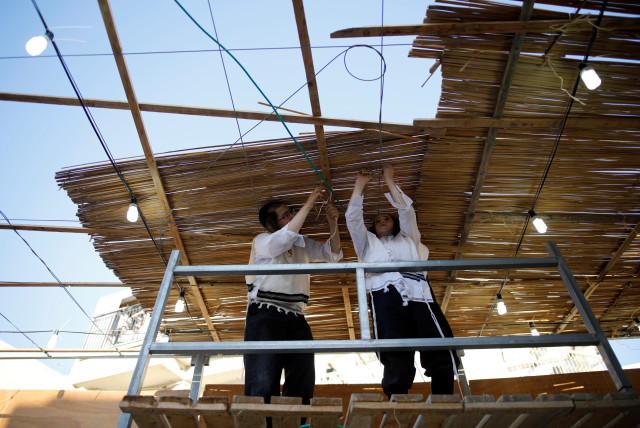  Ultra-Orthodox Jewish men build a ritual booth, known as a sukkah, used during the Jewish holiday of Sukkot, in Ashdod, Israel September 20, 2018. (credit: REUTERS/AMIR COHEN)