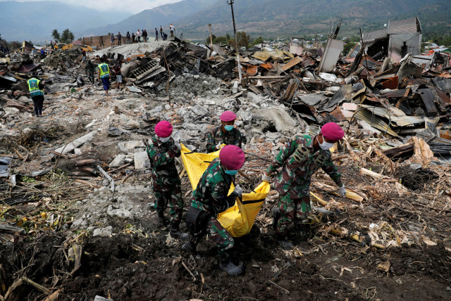 Indonesian soldiers carry a dead body from the ruins of houses after an earthquake hit Balaroa sub-district in Palu, Indonesia, October 4, 2018. (credit: REUTERS/Beawiharta)