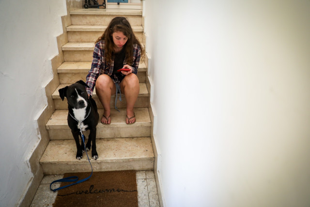  A woman and her dog takes cover in a stairway in Jerusalem, as a red Siren alert is sounded, when a rocket barrage is fired from Gaza into Israel, October 7, 2023.  (credit: NOAM REVKIN FENTON/FLASH90)