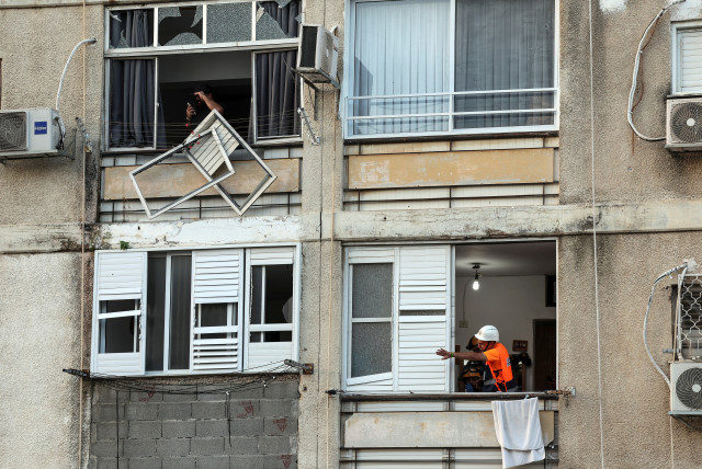  An Israeli emergency responder gestures from the window of a damaged building after a rocket, launched from the Gaza Strip into Israel landed in Ashkelon, southern Israel, October 10, 2023 (credit: REUTERS/Ronen Zvulun)