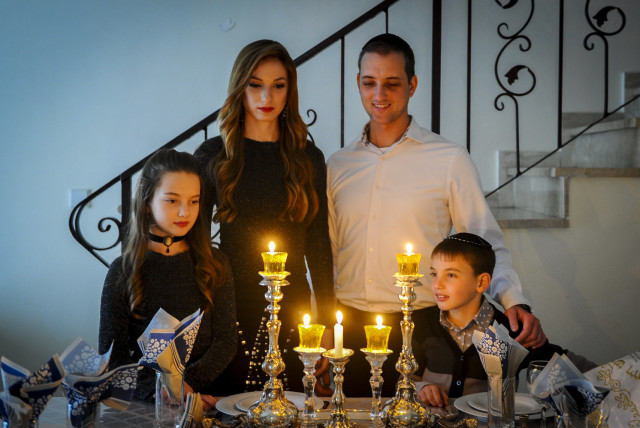 A FAMILY gathers around the Shabbat candles (credit: MENDY HECHTMAN/FLASH90)