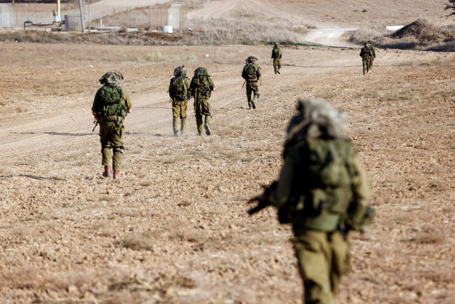  Israeli soldiers walk on grassy terrain near Israel's border with Gaza in southern Israel, October 12, 2023. (credit: REUTERS/AMIR COHEN)