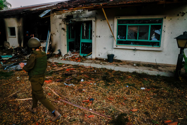  A SOLDIER passes yesterday in front of a burned home in Kibbutz Be’eri, whose family occupants were slaughtered by Hamas terrorists on Saturday. (credit: Chaim Goldberg/Flash90)