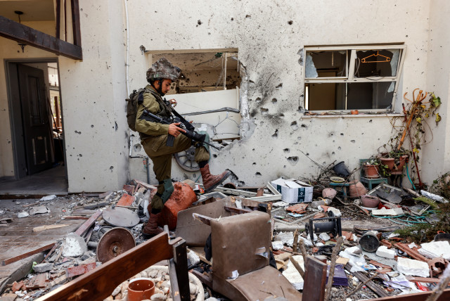  An Israeli soldier steps over personal belongings near a home, following a mass infiltration by Hamas gunmen from the Gaza Strip, in Kibbutz Beeri in southern Israel, October 13, 2023.  (credit: REUTERS/AMIR COHEN)