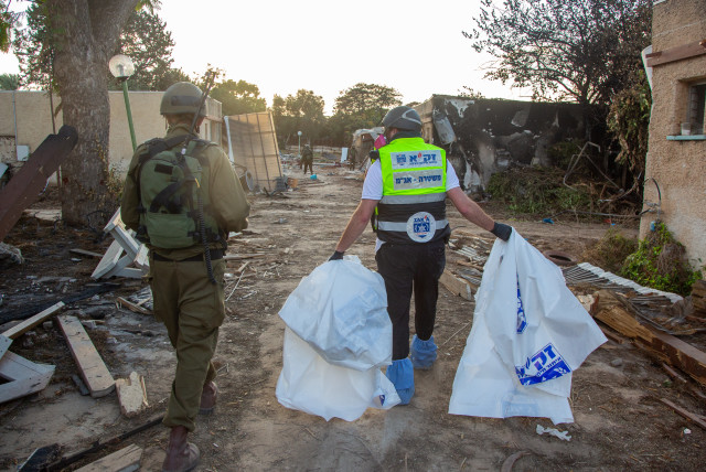  Members of Zaka walk through the destruction caused by Hamas Militants in Kibbutz Kfar Aza, as they collect the dead bodies, near the Israeli-Gaza border, in southern Israel, October 15, 2023.  (credit: EDI ISRAEL/FLASH90)