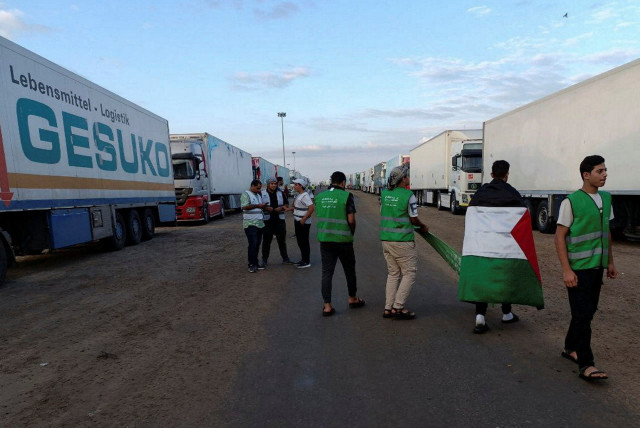  Egyptian volunteers gather with a Palestinian flag next to a truck convoy carrying humanitarian aid from Egyptian NGOs for Palestinians at the Rafah crossing, waiting for a decision for it to open, to enter Gaza, amid the ongoing conflict between Israel and the Palestinian Islamist group Hamas. (credit: REUTERS/STRINGER)