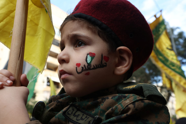 A boy holds a flag as Hezbollah supporters attend a protest, after hundreds of Palestinians were killed in a blast at Al-Ahli hospital in Gaza that Israeli and Palestinian officials blamed on each other, in Beirut's southern suburbs, Lebanon October 18, 2023. (credit: REUTERS/MOHAMED AZAKIR)
