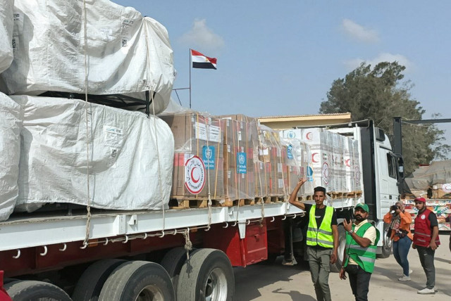  Egyptian Red Crescent members and volunteers gather next to a truck carrying humanitarian aid as it drives through the Rafah crossing from the Egyptian side, amid the ongoing conflict between Israel and the Palestinian Islamist group Hamas, in Rafah, Egypt October 22, 2023 (credit: REUTERS/STRINGER)