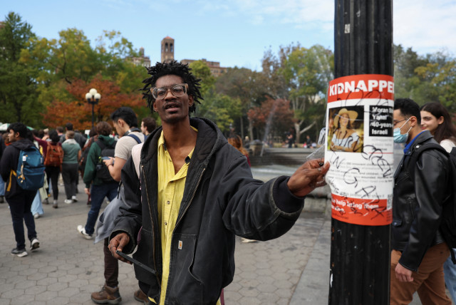 A man rips off a poster with a picture of a woman and the word ''kidnapped'', as part of a student walkout by students of New York University, in New York City, U.S., October 25, 2023.  (credit: REUTERS/SHANNON STAPLETON)
