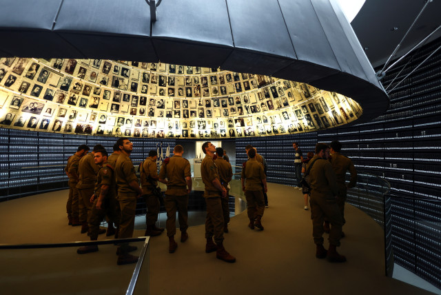  Israeli soldiers look up at pictures of victims of the Holocaust at the Yad Vashem Holocaust memorial centre, ahead of the Holocaust Remembrance Day starting this evening, at the Hall of Names, in Jerusalem April 27, 2022. (credit: REUTERS/Ronen Zvulun)