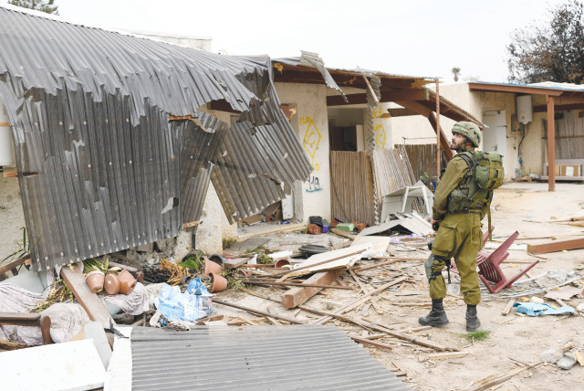  An IDF soldier looks at the destruction in Kibbutz Kfar Aza, one of the hardest-hit communities in the October 7 onslaught by Hamas. (credit: GILI YAARI/FLASH90)